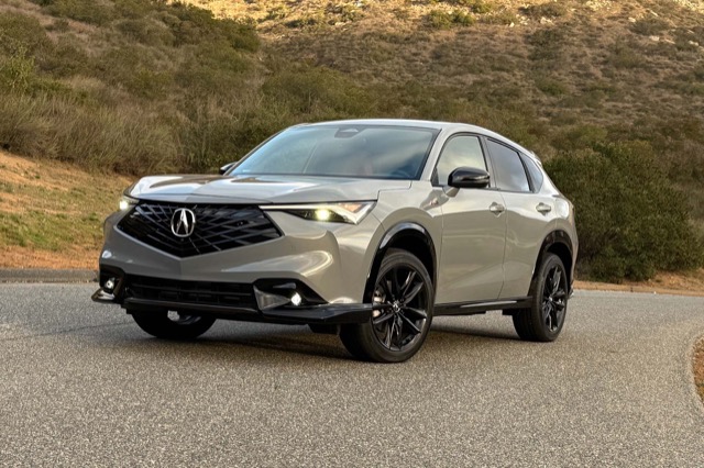 Front three-quarter view of a gray 2025 Acura ADX SUV parked on a paved road with hills.
