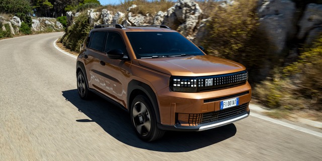Bronze 2025 Fiat Grande Panda hatchback driving along a curving paved road during daylight.
