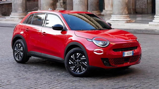 Red 2023 Fiat 600e suv parked on a cobblestone square in front of classical columns