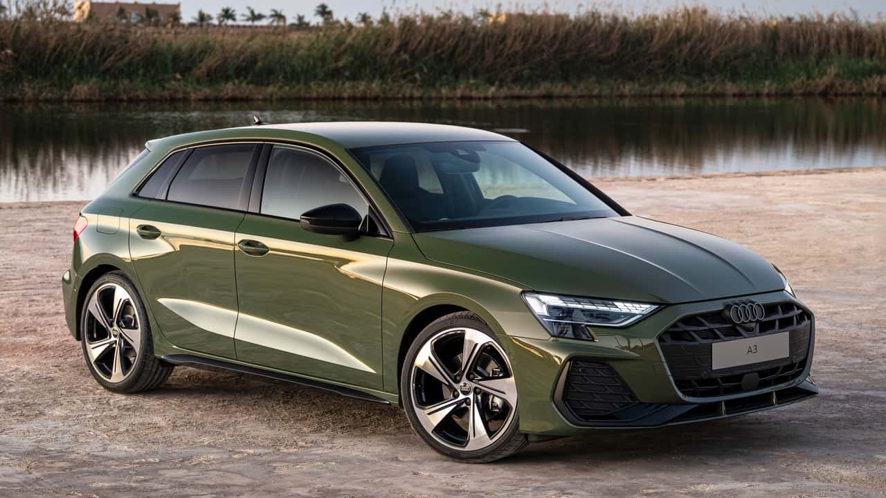 Three-quarter front view of a green 2024 Audi A3 Sportback hatchback parked near water outdoor.