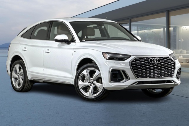 Front three-quarter view of a white 2024 Audi Q5 Sportback SUV parked outside a modern building.