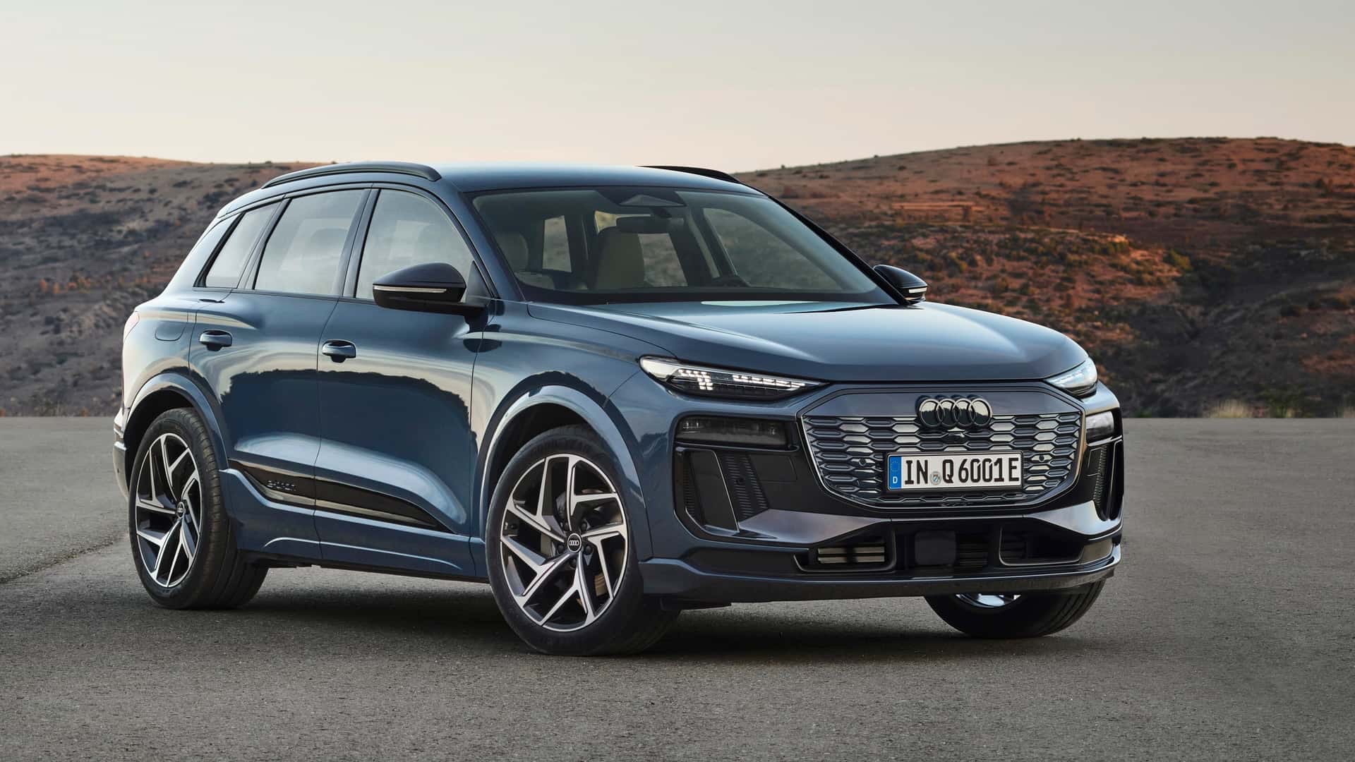 Blue 2024 Audi Q6 e-tron SUV shown in a front three-quarter view on paved ground.