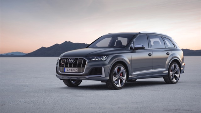 Front three-quarter view of a grey 2024 Audi Q7 SUV parked on an open desert landscape.