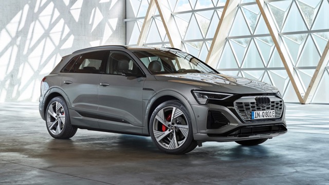 Front three-quarter view of a gray 2023 Audi Q8 SUV parked inside a modern architectural space.