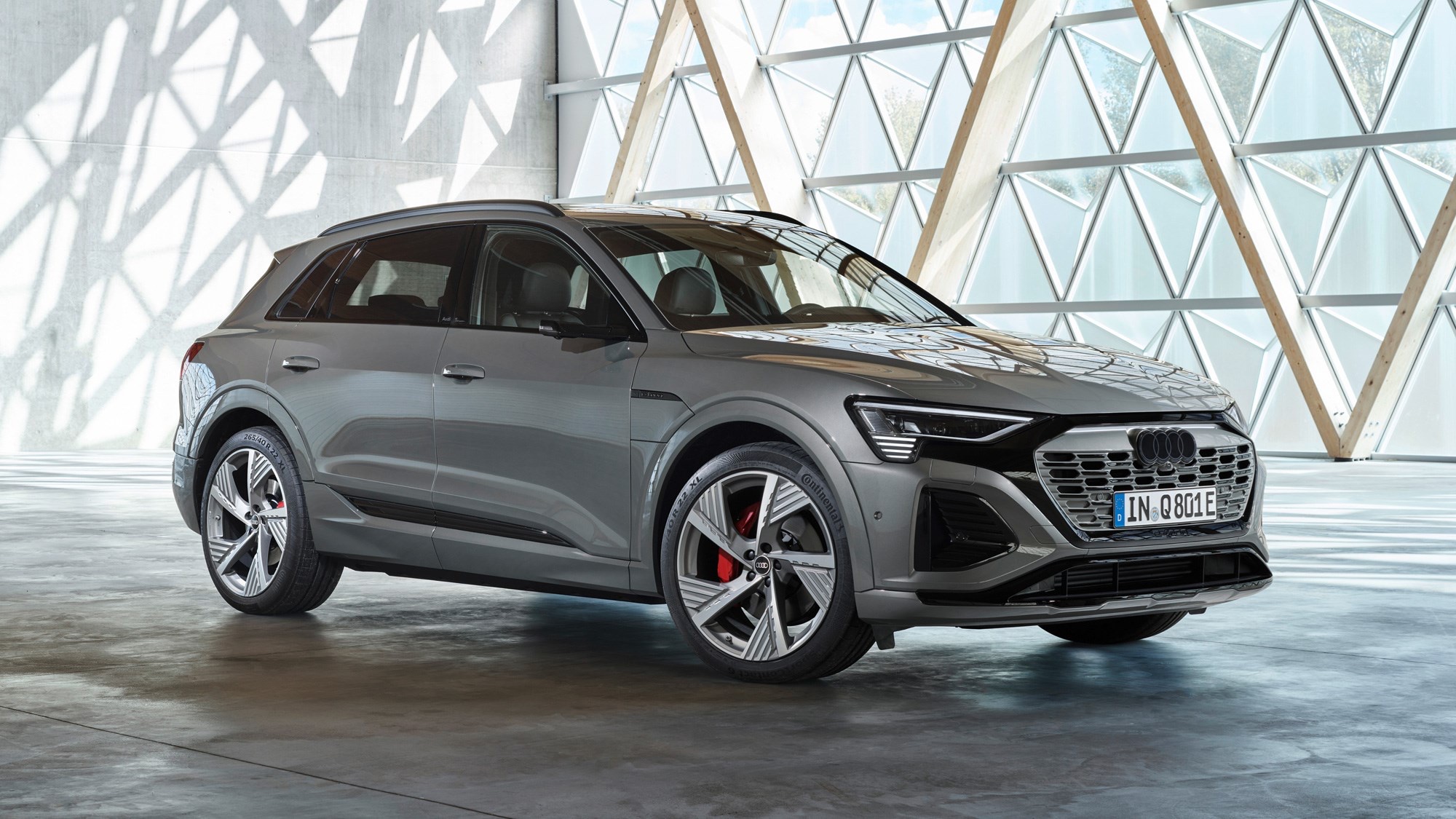 Front three-quarter view of a gray 2023 Audi Q8 SUV parked inside a modern architectural space.