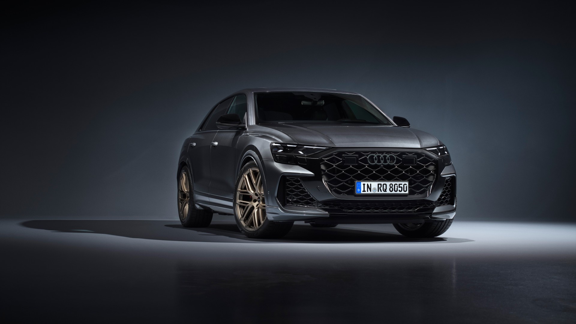 Front three-quarter view of a dark gray 2024 Audi RS Q8 SUV parked in a studio setting.