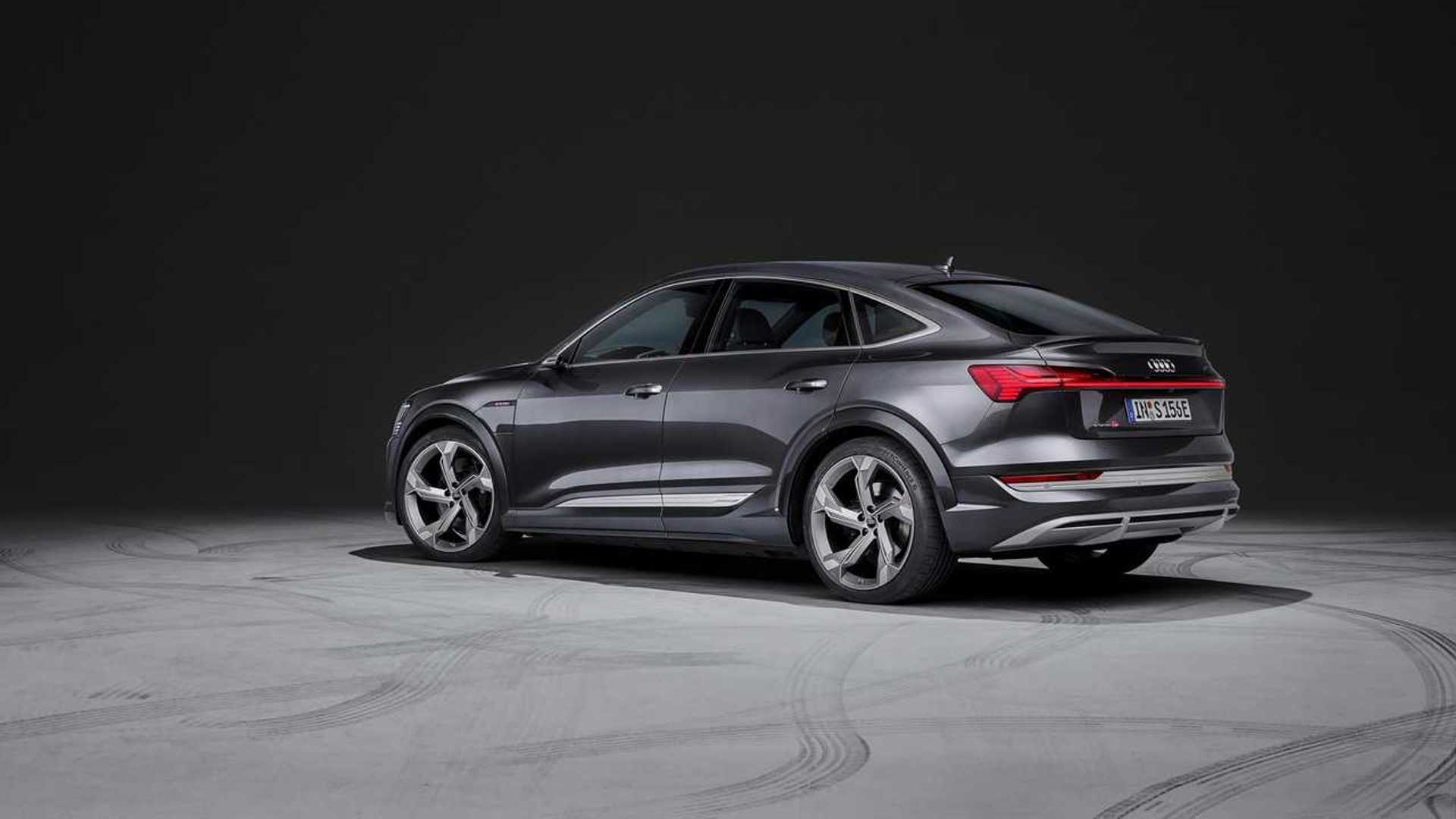Rear three-quarter view of a dark grey Audi e-tron S Sportback parked in a minimalist indoor studio.