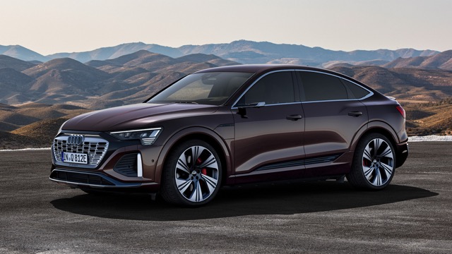 Front three-quarter profile of a brown 2022 Audi Q8 Sportback e-tron SUV parked against mountains.