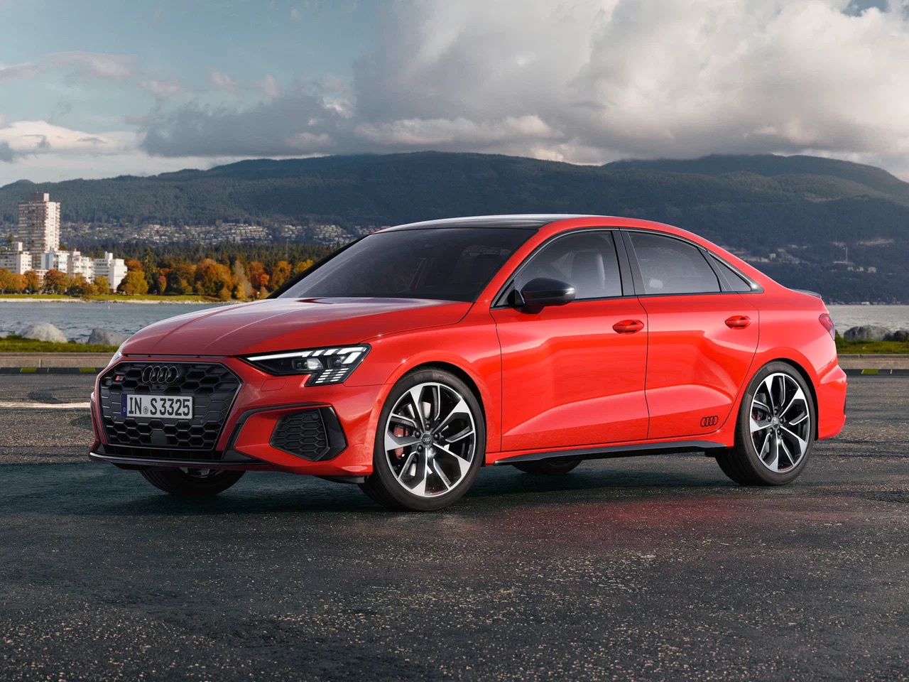 Front three-quarter view of a red Audi S3 Sedan parked outdoors with mountains in the background.