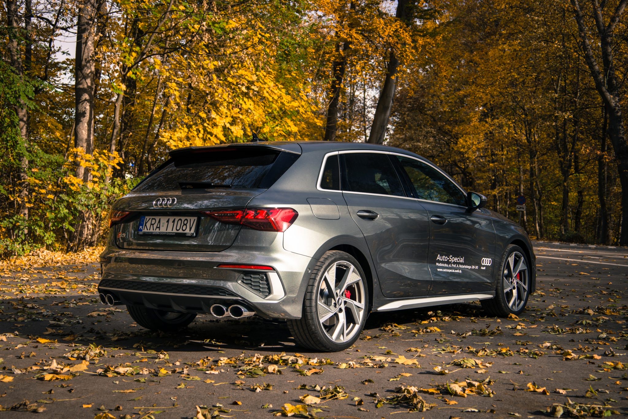 Gray Audi S3 Sportback hatchback side profile on autumn road.