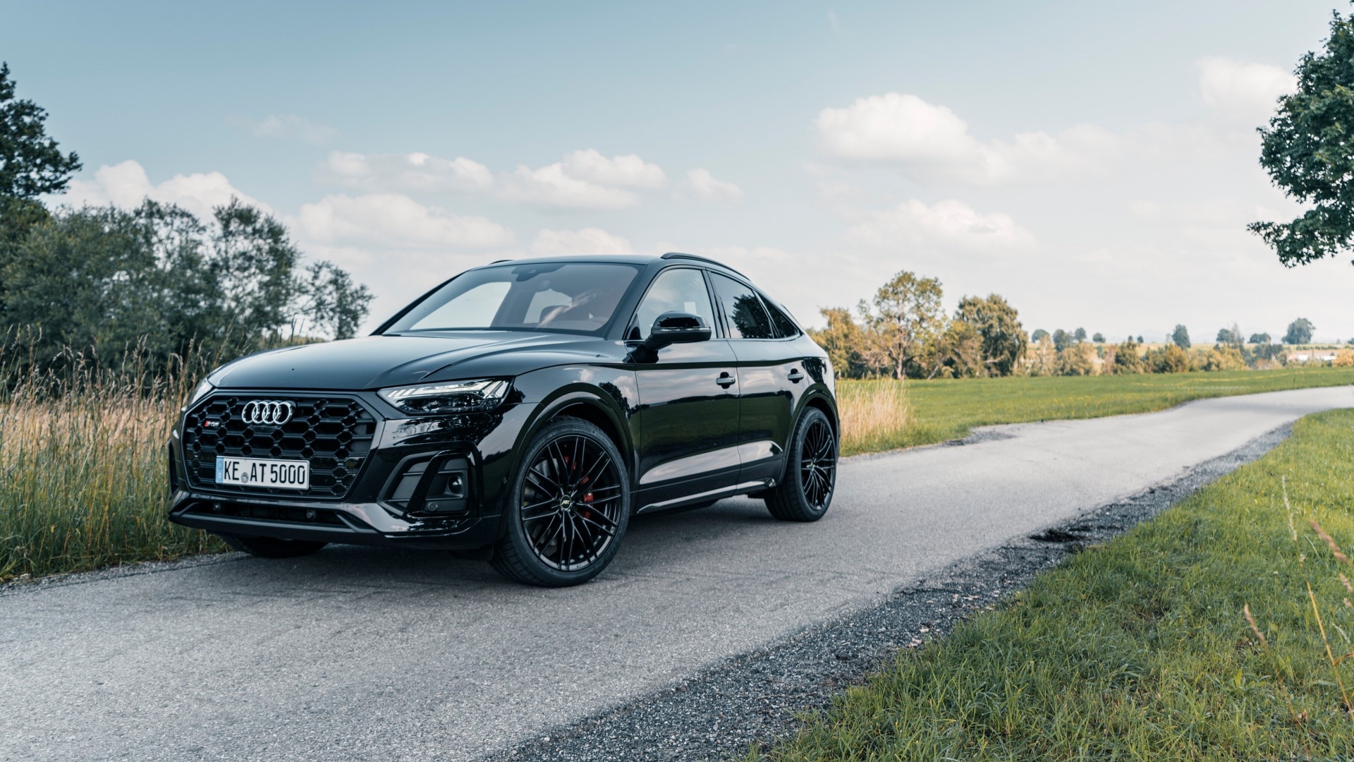 Black Audi SQ5 Sportback side profile on rural road.