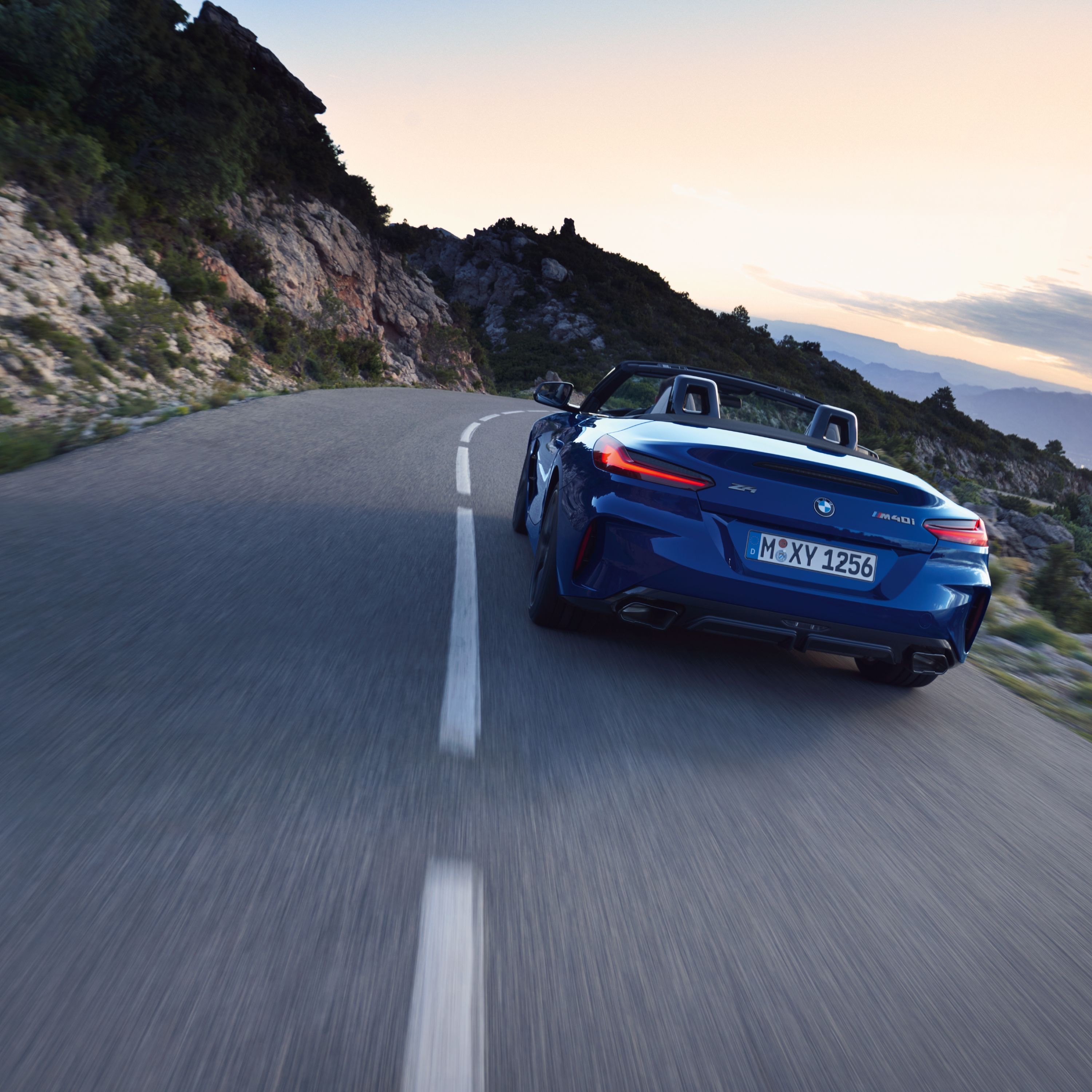 Rear three-quarter view of a blue 2022 BMW Z4 Roadster driving along a mountain road.