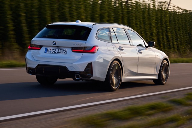 Rear three-quarter view of a white 2022 BMW 3 Series Touring driving on an open road.