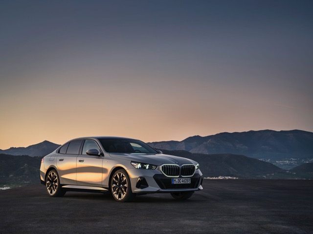 Front three-quarter view of a silver 2023 BMW 5 Series Sedan parked outdoors at dusk.