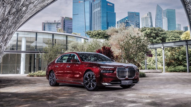 Red 2022 BMW 7 Series sedan parked outdoors with city skyscrapers in the background
