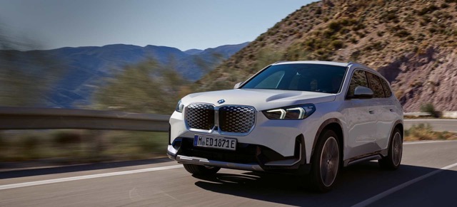 Front three-quarter view of a white 2022 BMW iX1 driving on a paved road.
