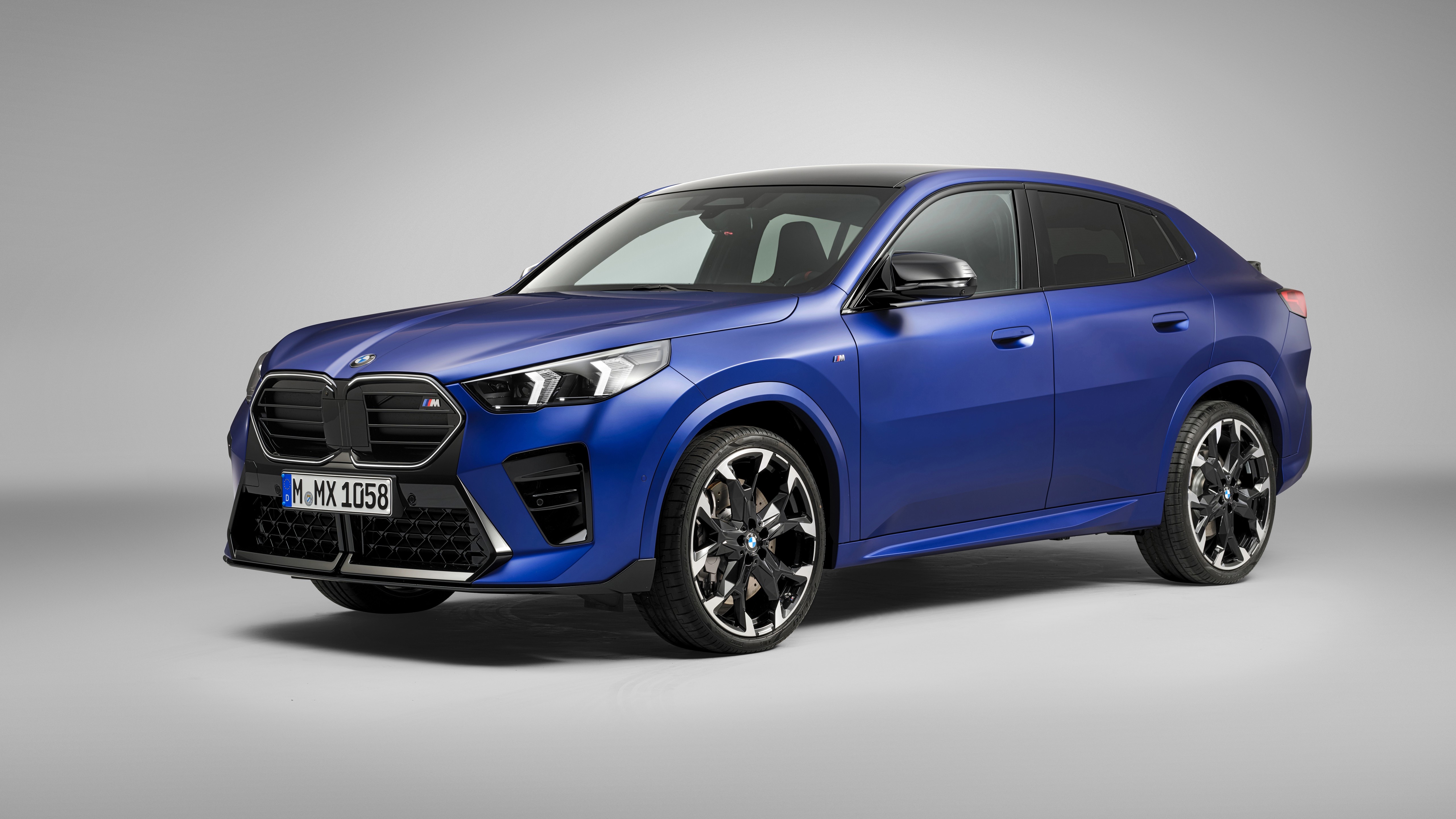 Front three-quarter view of a blue 2023 BMW X2 SUV parked in a plain studio setting