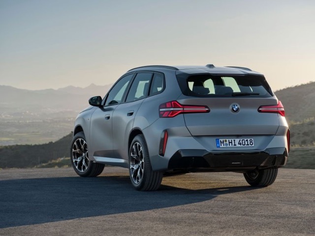 Rear three-quarter view of a grey 2024 BMW X3 SUV parked outdoors on a hill.