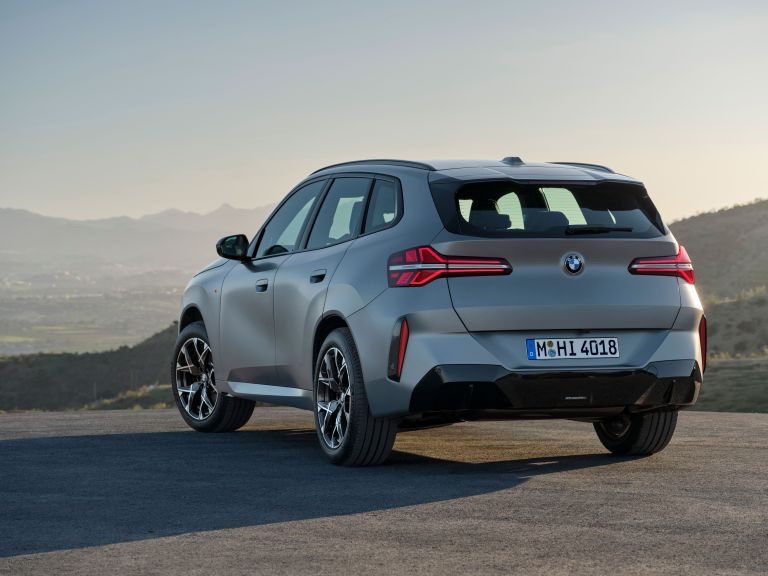 Rear three-quarter view of a grey 2024 BMW X3 SUV parked outdoors on a hill.