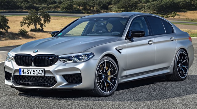 Front three-quarter view of a silver 2020 BMW M5 Sedan on an open asphalt track.