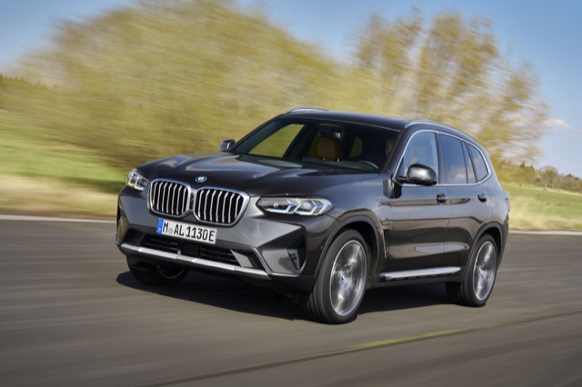 Front three-quarter view of a dark grey 2021 BMW X3 SUV driving on an open road.