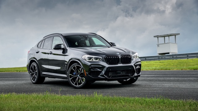Front three-quarter view of a dark grey 2021 BMW X4 M (F98) SUV parked on an asphalt track.