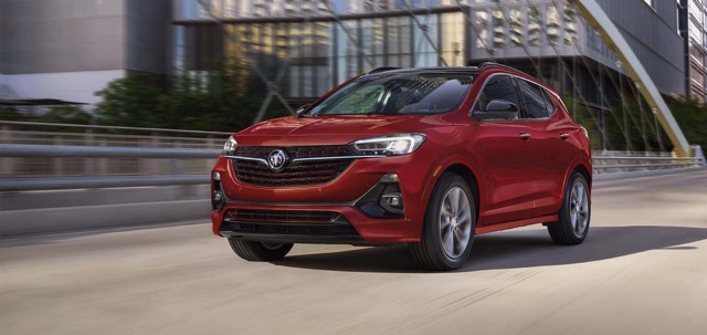 Front three-quarter view of a red 2023 Buick Encore GX driving on an urban road.