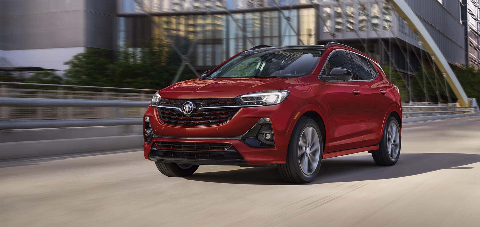 Front three-quarter view of a red 2023 Buick Encore GX driving on an urban road.